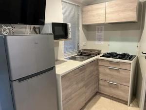 a small kitchen with a refrigerator and a sink at Camping Le Lizot - Aquatique Vacances in Saint-Mandé-sur-Brédoire