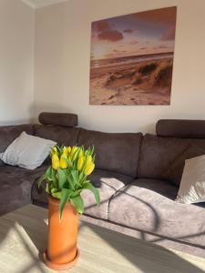 an orange vase with yellow flowers on a table in a living room at Haus Friesenliebe in Greetsiel +25 photos