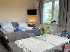 a room with two beds and a table with flowers on it at Błękitna Przystań - pokoje z widokiem na Zatokę in Swarzewo +73 photos