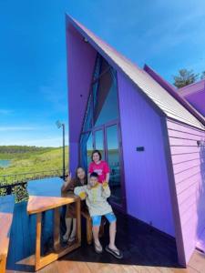 three girls standing on the front of a purple house at Hồ Mây Homestay in Bảo Lâm