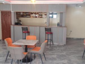 a bar with orange chairs and a table and a counter at Southwest Hotel-Kilgoris in Kilgoris