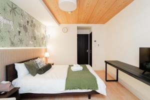 a bedroom with a bed and a flat screen tv at QUEENS PARK in Osaka