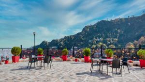 un patio con tavoli e sedie con montagne sullo sfondo di Basera Hotel a Mussoorie