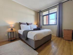a bedroom with a large bed and a window at Beach Loft Empire Apartment in Muizenberg