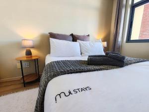 a bedroom with two beds with white pillows and a window at Beach Loft Empire Apartment in Muizenberg