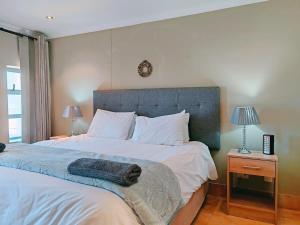 a bedroom with a large bed with a blue headboard at Sunrise Deck Empire Apartment in Muizenberg