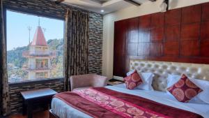 una camera da letto con un letto grande con una grande finestra di Basera Hotel a Mussoorie