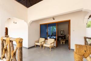 sala de estar de planta abierta con sillas y mesa en The Soul Zanzibar Beach Hotel & Spa, en Pwani Mchangani Mdogo