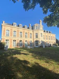 a large brick building on top of a grass field at Hôtel et SPA du Château in Lagord