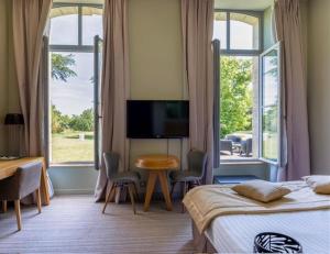 a bedroom with two beds and a table and a television at Hôtel et SPA du Château in Lagord