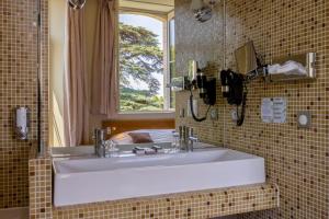 a bathroom with a white sink and a window at Hôtel et SPA du Château in Lagord