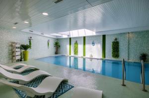 a pool with white chairs and a swimming pool at Hôtel et SPA du Château in Lagord