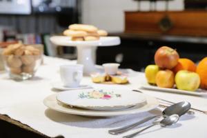 a table with plates and utensils and fruit on it at B&B Le Mongolfiere in Paulilatino