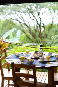 a wooden table with cups and plates of food on it at Sueño Río Celeste Boutique B&B in Bijagua