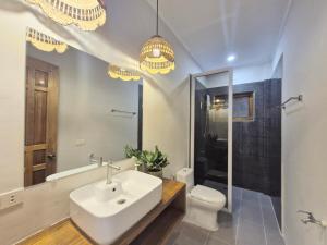 a bathroom with a sink and a toilet and chandeliers at Sing Siargao in General Luna +98 photos