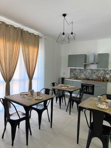 una sala da pranzo con tavoli e sedie e una cucina di Tropical House a Gizzeria