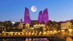 Una luna sobre una ciudad con edificios altos y farolas en Aden City Hotel, en Baku