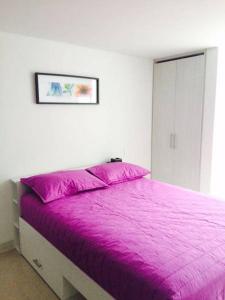 a bedroom with a bed with a purple blanket at Rent Apartments Manizales in Manizales