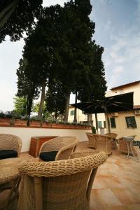 un patio con sillas, mesas y una sombrilla en Hotel Bologna, en Pisa