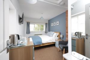 a bedroom with a bed and a desk with a tv at Berwick House in Sidmouth