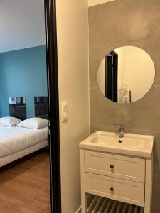 a bathroom with a sink and a mirror and a bed at Onyx Grey in Saint-Aignan