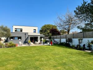 une maison avec une pelouse devant dans l'établissement Belle maison spacieuse et jardin paysager, Gouesnac'h, à Gouesnach