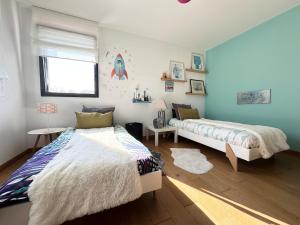 - 2 lits dans une chambre dotée de murs bleus et de parquet dans l'établissement Belle maison spacieuse et jardin paysager, Gouesnac'h, à Gouesnach