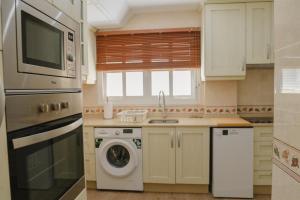 a kitchen with a washing machine and a microwave at Apartamento The River in El Puerto de Santa María +16 photos