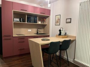 a kitchen with purple cabinets and a wooden table with two chairs at La Promenade in Beaupréau