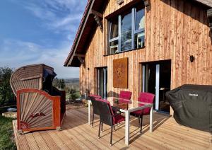 a wooden deck with a table and chairs on it at TOP moderne FeWo - Alpakahof zum Himmelreich, traumhafte Lage, Terrasse mit Weitblick, kostenfreier Parkplatz, Nähe Kurklinik, optional Sauna in Bad Gottleuba