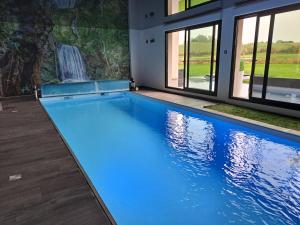 a swimming pool with blue water in a house at Emille et une nuits in Mérignies