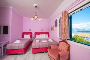 two beds in a room with pink walls and a window at Bella Vista in Nydri