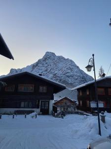 a snow covered mountain in front of a building at Appartamento Netta'Schtol in Sappada
