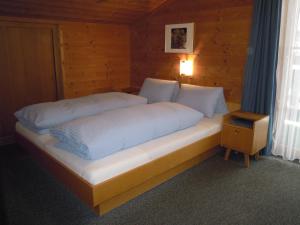 a bed with white sheets and pillows in a room at Pension Herzoggut in Zell am See