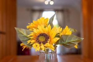 a vase filled with yellow sunflowers on a table at Abbey Farm House - Pet Friendly in Ormskirk +16 photos