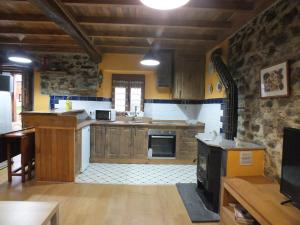 a kitchen with wooden cabinets and a stone wall at Apartamentos Rurales Casa Llucas in San Julián