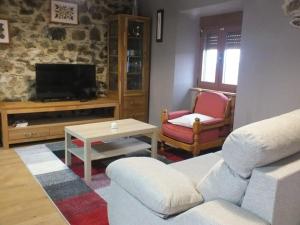 a living room with a couch and a tv at Apartamentos Rurales Casa Llucas in San Julián