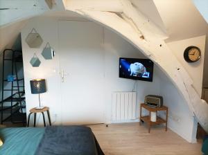 a bedroom with a bed and a tv on a wall at Studio cosy Piscine Rocherfort en Terre Centre in Rochefort-en-Terre