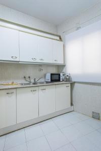 a kitchen with white cabinets and a microwave at Apartamento Casa Puerta del Sol I in Montijo