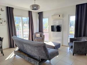 a living room with a couch and chairs and a tv at Paddys Apartments, Hisarönü in Fethiye