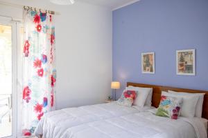 a bedroom with a bed with white sheets and a window at Stefanie Studios in Egina
