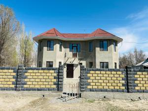 a house with a brick fence in front of it at Meimanbek Guesthouse in Jangy-Talap