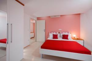 a red and white bedroom with a red bed at Apartments and rooms Mlikota in Promajna