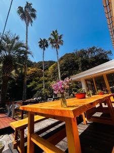 a wooden picnic table with flowers on it with palm trees at The Surf Lodge White Beach in Shimoda