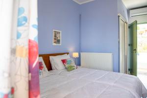 a blue bedroom with a large bed with white sheets at Stefanie Studios in Egina