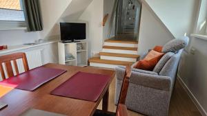 a living room with a dining room table and a room with a staircase at FeWo Gisela in Fehmarn