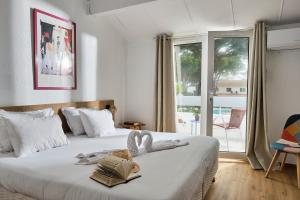 a bedroom with two beds and a large window at Artemia Aigues-Mortes - Hôtel avec piscine - Bornes électriques - Parking privé - Local vélo-moto in Aigues-Mortes +22 photos
