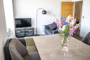 a living room with a table with a vase of flowers at Stunning 2 Bed Manchester Apartment Near Etihad in Manchester +22 photos