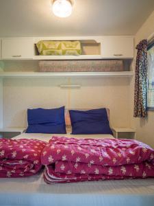 a large bed with purple sheets and blue pillows at Mobile Home auf Campingplatz mit Naturbadesee in Parsac