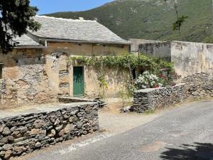 a stone house with a green door and a stone wall at Maison ancienne rénovée avec vue sur mer et Cap Corse in Centuri +28 photos